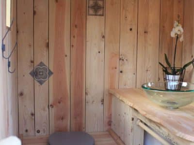 Hébergement insolite en bois en Auvergne-Rhône-Alpes, avec lavabo en verre et orchidée.