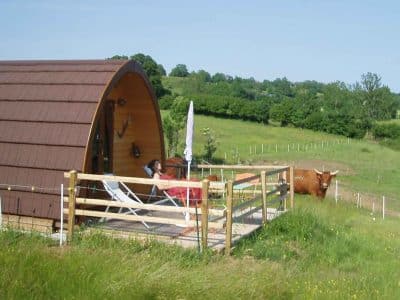 Cabane en bois en Auvergne, avec terrasse et vue sur la nature verdoyante.