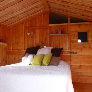 Cabane en bois chaleureuse avec un lit douillet et des coussins colorés.