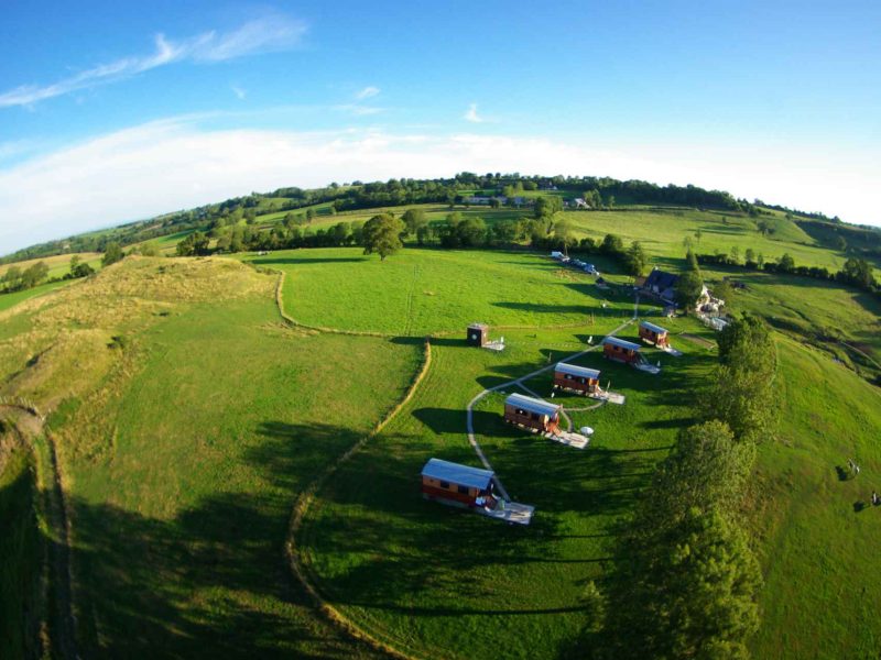 Hébergements insolites en Auvergne, cabanes en bois sur un terrain verdoyant.