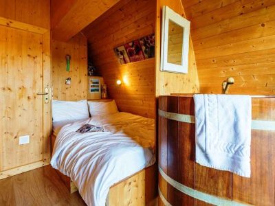 Chalet en bois avec lit douillet et baignoire en bois, ambiance chaleureuse.