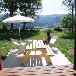 Hébergement insolite en Auvergne avec terrasse en bois et vue panoramique sur la vallée.