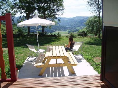 Hébergement insolite en Auvergne avec terrasse en bois et vue panoramique sur la vallée.