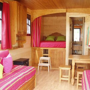Cabane en bois cosy en Auvergne, avec des coussins colorés et une vue charmante.