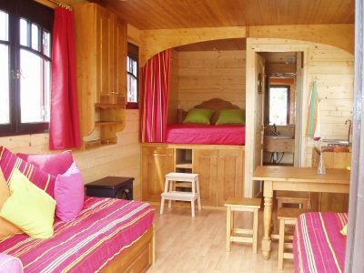 Cabane en bois cosy en Auvergne, avec des coussins colorés et une vue charmante.