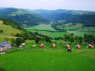 Hébergement insolite en Auvergne : cabanes colorées au milieu dun paysage verdoyant.