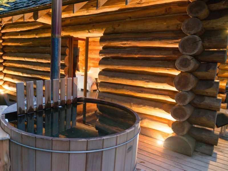 Cabane en bois avec un bain nordique en bois sur une terrasse accueillante.