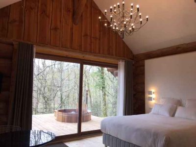 Cabane en bois avec vue sur la forêt et un jacuzzi sur la terrasse.