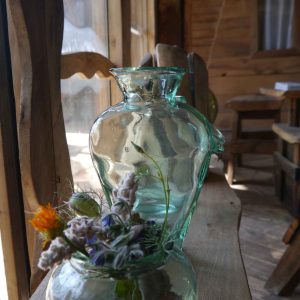 Vase en verre avec fleurs séchées dans un hébergement insolite en bois.