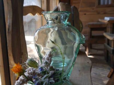 Vase en verre avec fleurs séchées dans un hébergement insolite en bois.