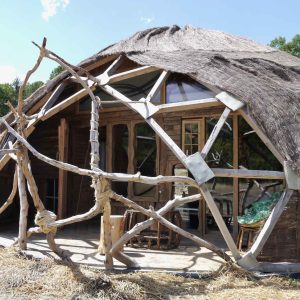 Hébergement insolite en forme de dôme, avec une structure en bois et toit de chaume.