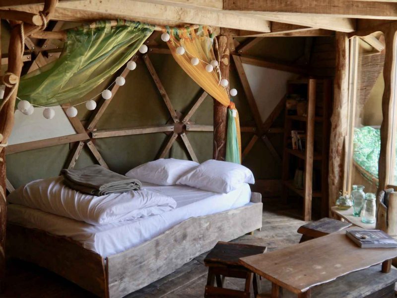 Hébergement insolite en cabane avec lit en bois et décoration naturelle chaleureuse.