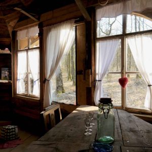 Cabane en bois dans les arbres, avec de grandes fenêtres et une vue sur la forêt.