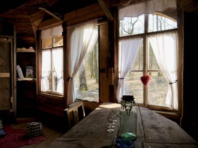 Cabane en bois dans les arbres, avec de grandes fenêtres et une vue sur la forêt.