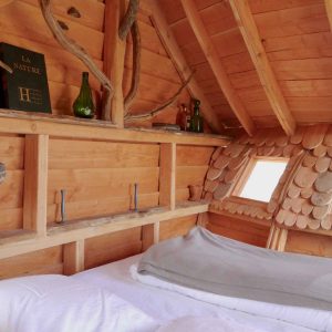 Cabane en bois cosy avec un lit douillet et des éléments naturels décoratifs.