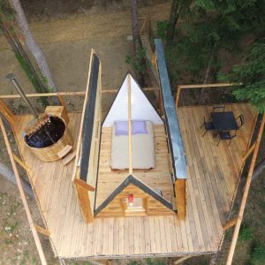 Cabane perchée en bois avec jacuzzi, offrant une vue imprenable sur la nature.