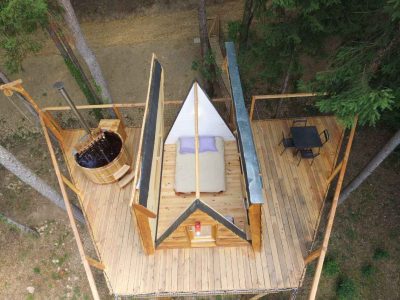 Cabane perchée en bois avec jacuzzi, offrant une vue imprenable sur la nature.
