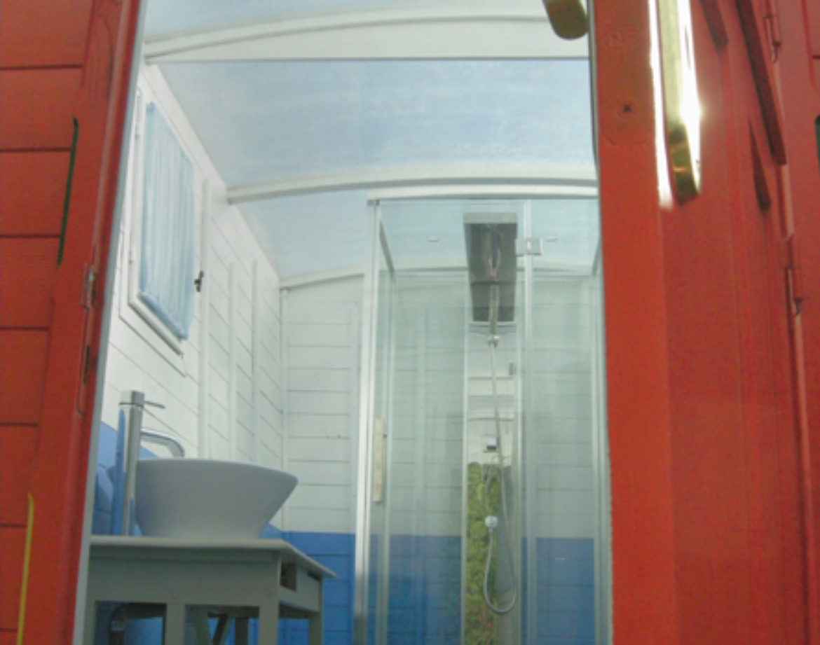 Hébergement insolite en Bourgogne : cabane colorée avec douche moderne et vue dégagée.