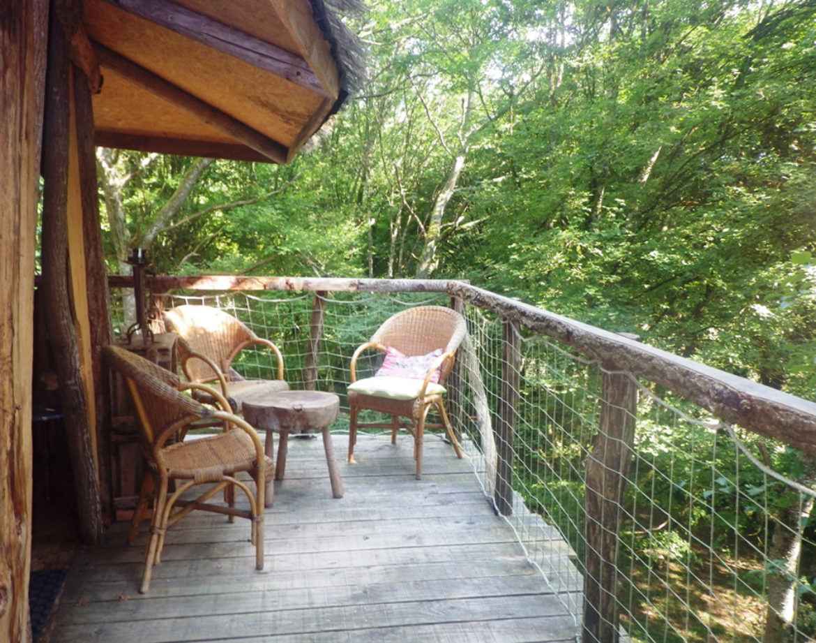 Cabane perchée en Bourgogne avec terrasse en bois et vue sur la verdure environnante.