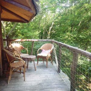 Cabane perchée en Bourgogne avec terrasse en bois et vue sur la verdure environnante.