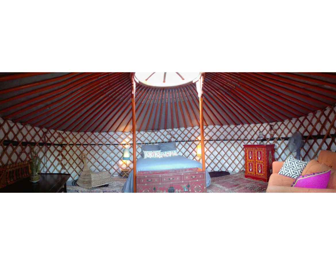 Yourte colorée et chaleureuse, avec un lit douillet et des décorations artisanales.