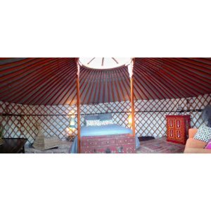 Yourte colorée et chaleureuse, avec un lit douillet et des décorations artisanales.