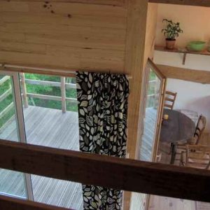 Cabane en bois avec balcon, décorée de plantes et lumière douce.