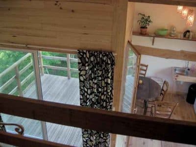 Cabane en bois avec balcon, décorée de plantes et lumière douce.