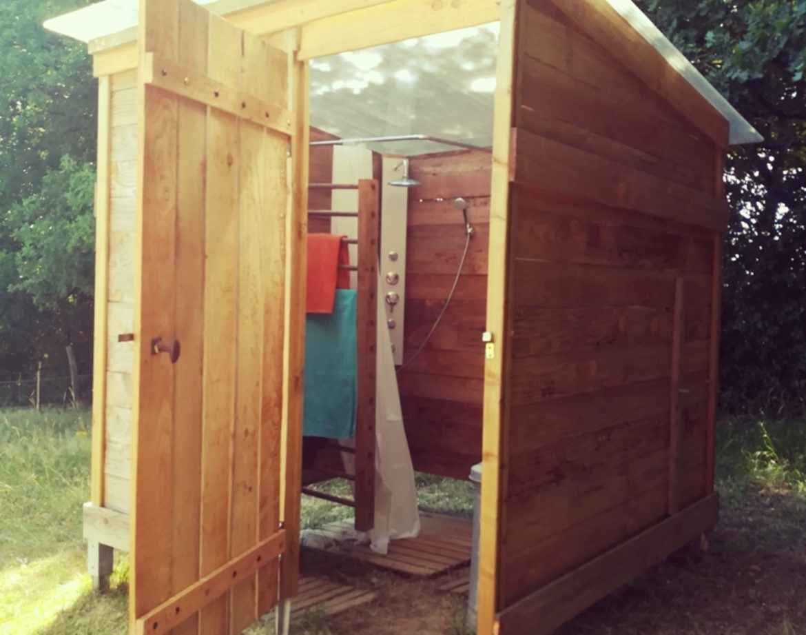 Cabane en bois à Bourgogne, avec une porte ouverte et une douche extérieure.
