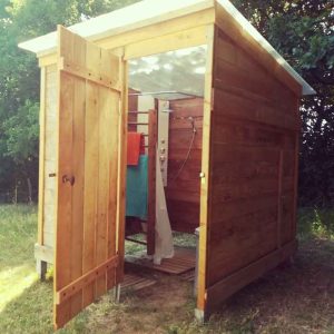 Cabane en bois à Bourgogne, avec une porte ouverte et une douche extérieure.