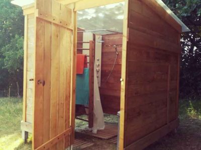 Cabane en bois à Bourgogne, avec une porte ouverte et une douche extérieure.