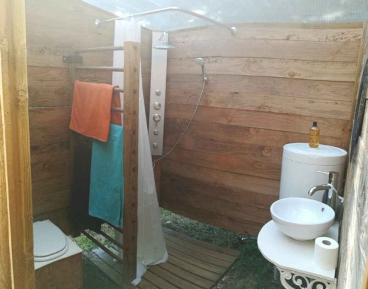 Douche extérieure en bois dans un hébergement insolite en Bourgogne.