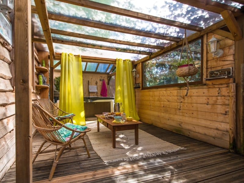 Cabane en bois avec un coin salon lumineux et des rideaux jaunes.