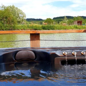 Hébergement insolite en Bourgogne avec jacuzzi, vue sur un lac et des collines verdoyantes.