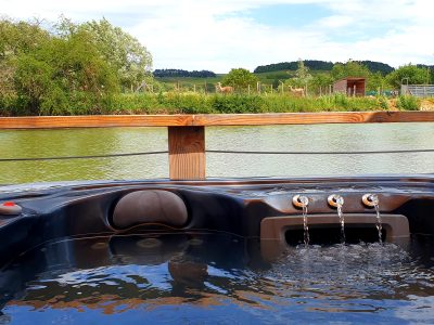 Hébergement insolite en Bourgogne avec jacuzzi, vue sur un lac et des collines verdoyantes.