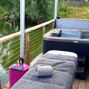 Hébergement flottant avec spa, terrasse en bois et vue sur la rivière.