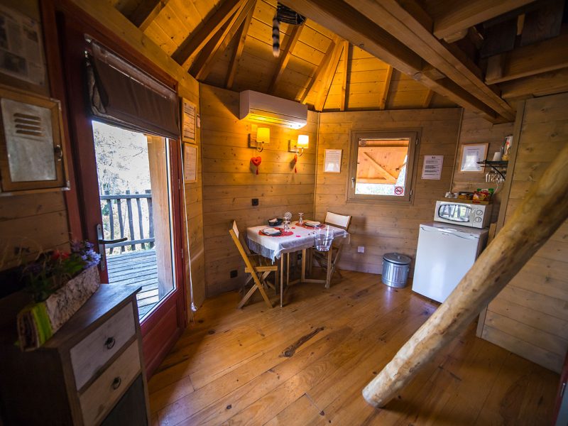 Chalet en bois chaleureux avec coin repas et vue sur la nature.