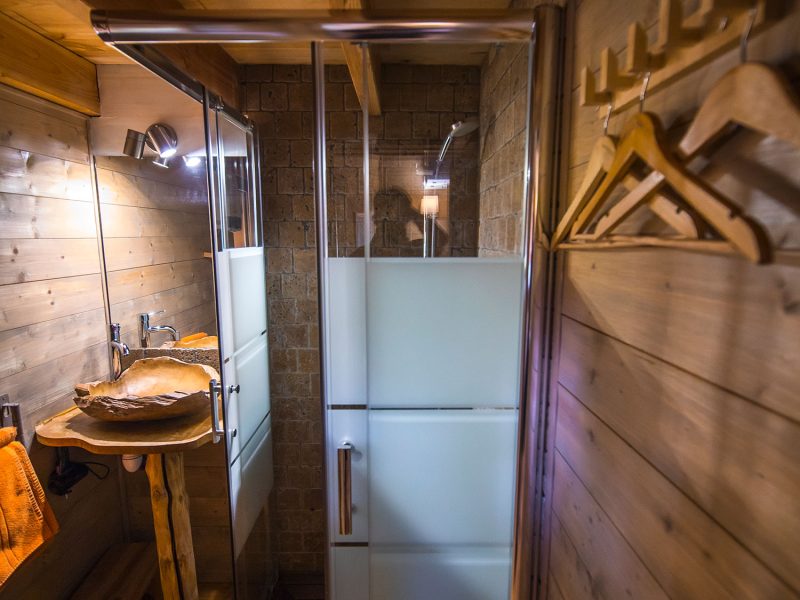 Salle de bain dun chalet en bois, avec douche moderne et décor chaleureux.