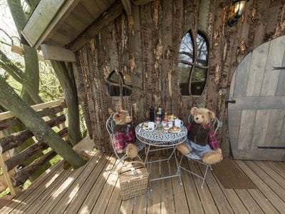 Cabane en bois perchée, décorée de peluches, avec une table pour le petit-déjeuner.