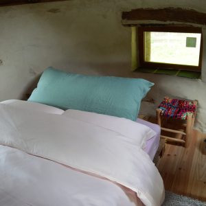 Chambre cosy en cabane, avec lit douillet et fenêtre offrant une vue sur la nature.