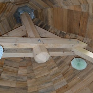 Intérieur dun hébergement insolite en bois à Midi-Pyrénées, avec un plafond en forme de cône.