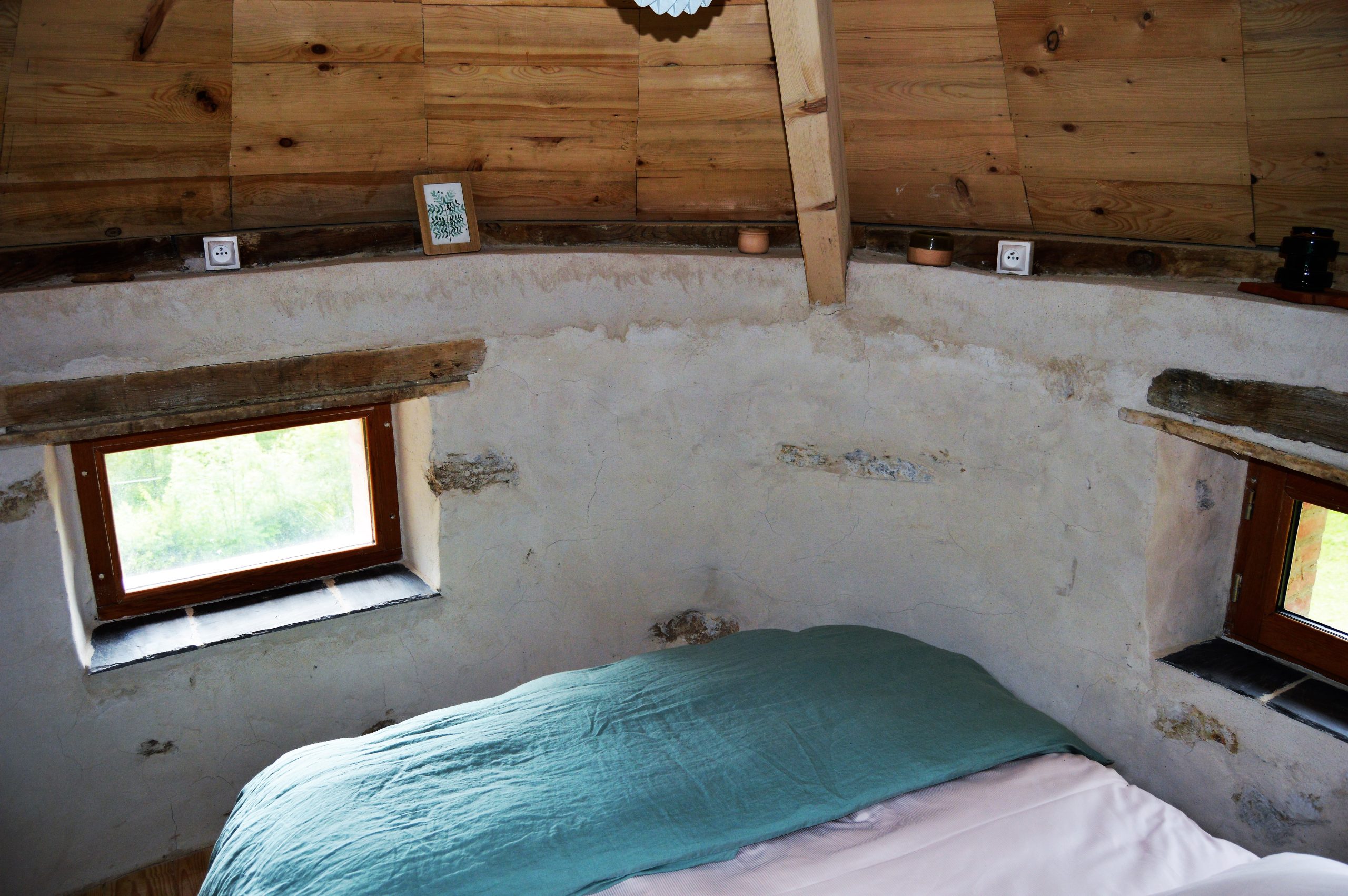 DSC_0349 Chalet en bois avec murs en pierre, lit douillet et fenêtres lumineuses.