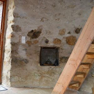 Hébergement insolite en pierre avec un escalier en bois et une vue sur la nature.