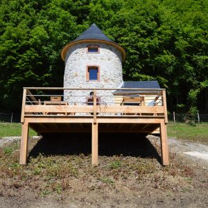 Moulin en pierre avec terrasse en bois, entouré de verdure à Midi-Pyrénées.