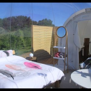 Hébergement insolite en bulle transparente, lit douillet et vue sur la nature.