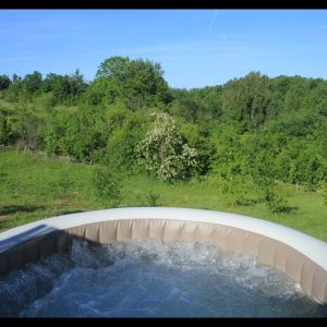 Hébergement insolite en Midi-Pyrénées avec jacuzzi et vue sur la verdure environnante.