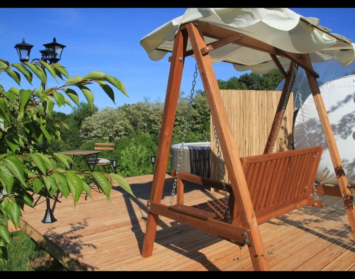 Hébergement insolite en Midi-Pyrénées : une balançoire en bois sur une terrasse ensoleillée.