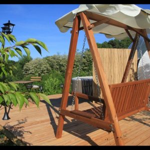 Hébergement insolite en Midi-Pyrénées : une balançoire en bois sur une terrasse ensoleillée.