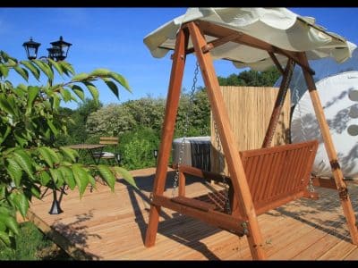 Hébergement insolite en Midi-Pyrénées : une balançoire en bois sur une terrasse ensoleillée.