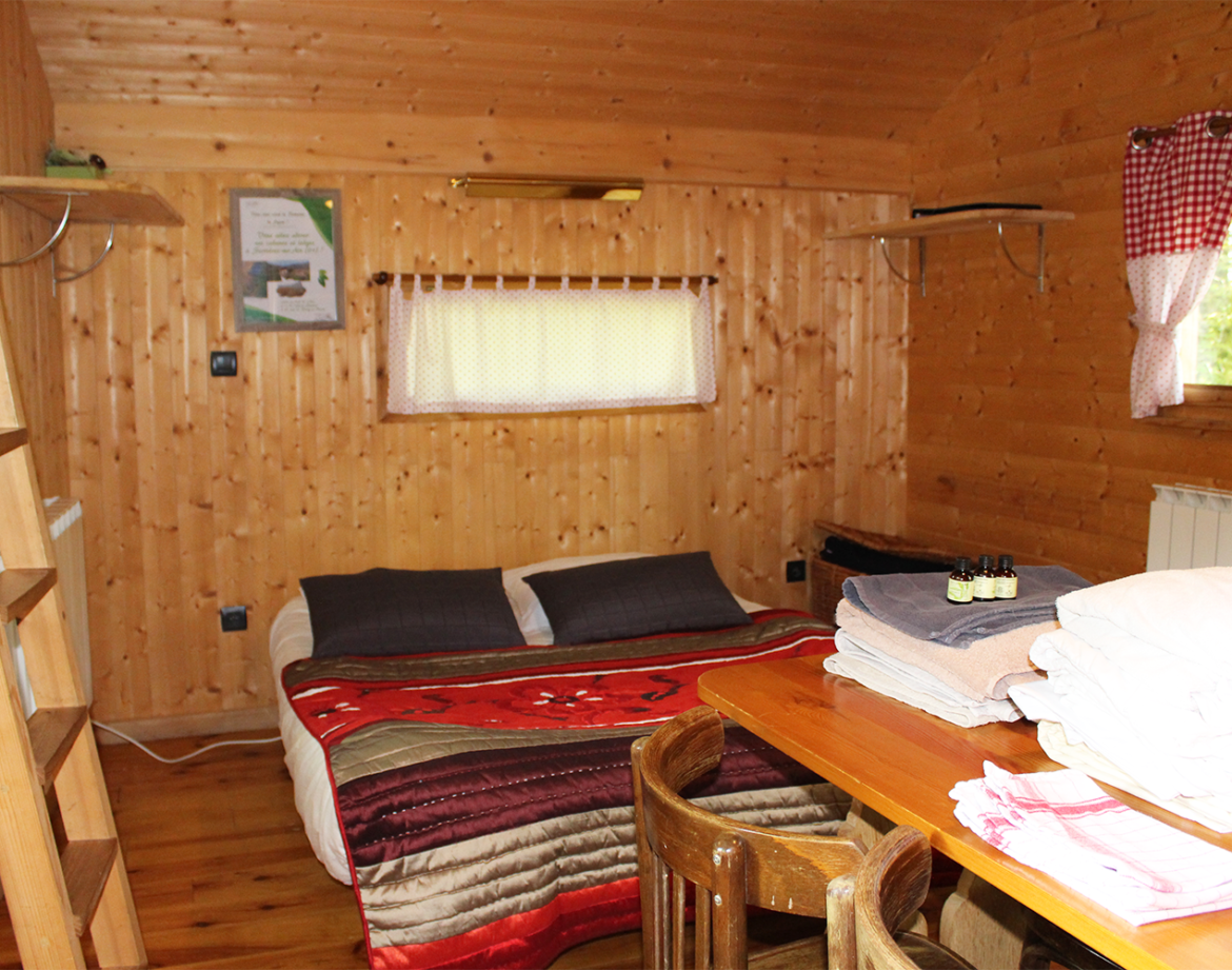 Chalet en bois chaleureux avec lit douillet et décoration rustique à Bourgogne-Franche-Comté.
